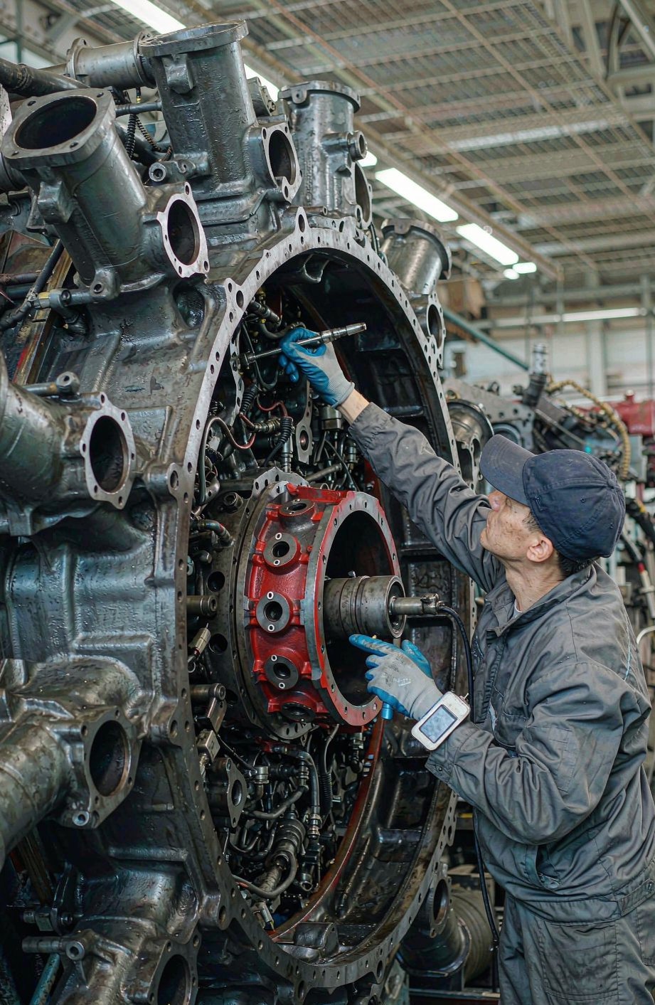 Technician servicing a large engine cylinder assembly in the workshop